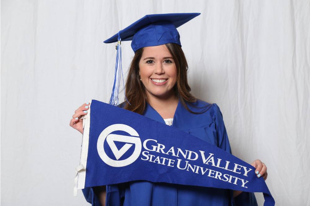Upcoming graduate posing with the GV flag at GradFest